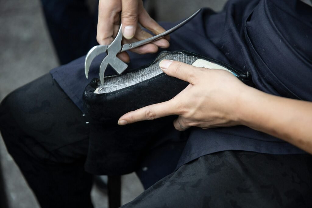 Close-up of a craftsman repairing a leather shoe with a cobbler's plier.